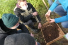 Drei Schüler betrachten Erdkrumen