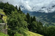 Bewaldeter Hang, darüber Wolken 